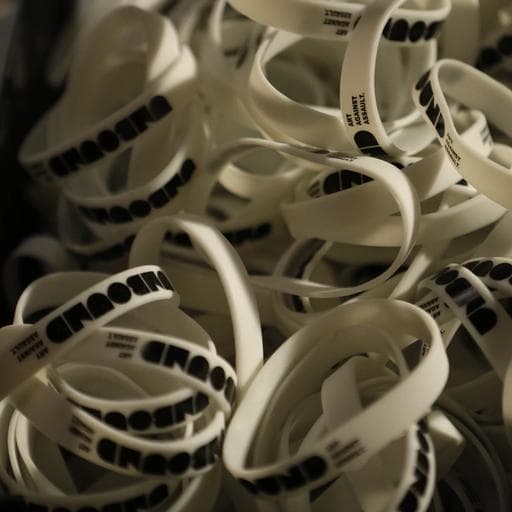 Pile of white silicone wristbands printed with black UNBOUND text.