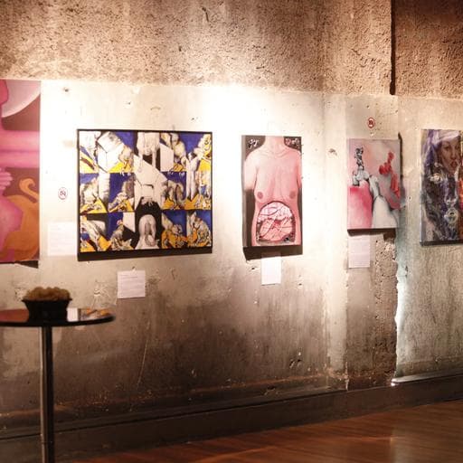 Four colorful figurative paintings hung on concrete gallery wall with labels.