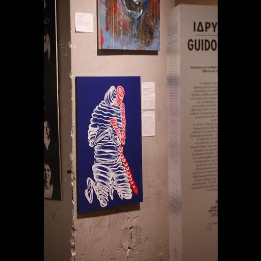 Blue painting of white bandaged figure with red accents beside GUIDO text panel.