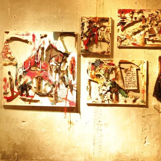 Four abstract mixed-media paintings with red, black and white shapes on gallery wall.