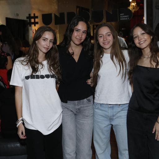 Four young women posing together in front of hashtag UNBOUND sign at gallery event.