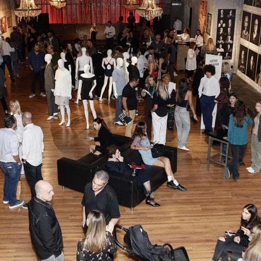 Overhead view of crowded gallery with white mannequins, couches and portrait walls.