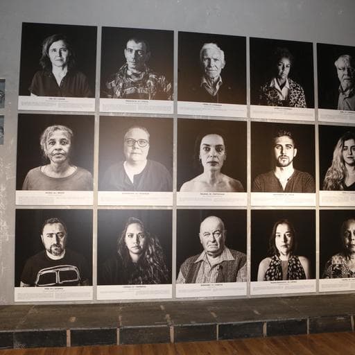Wall grid of fifteen black-and-white portrait photographs with text captions below.