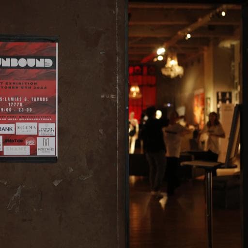 Unbound exhibition poster on wall with blurred visitors inside industrial gallery space.